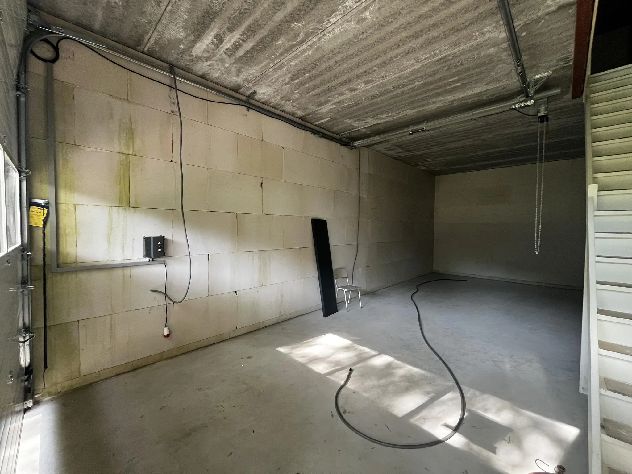 Leegstaand magazijn aan de Broekdijk West met betonnen vloer, onafgewerkte muren, kabels en een trap.